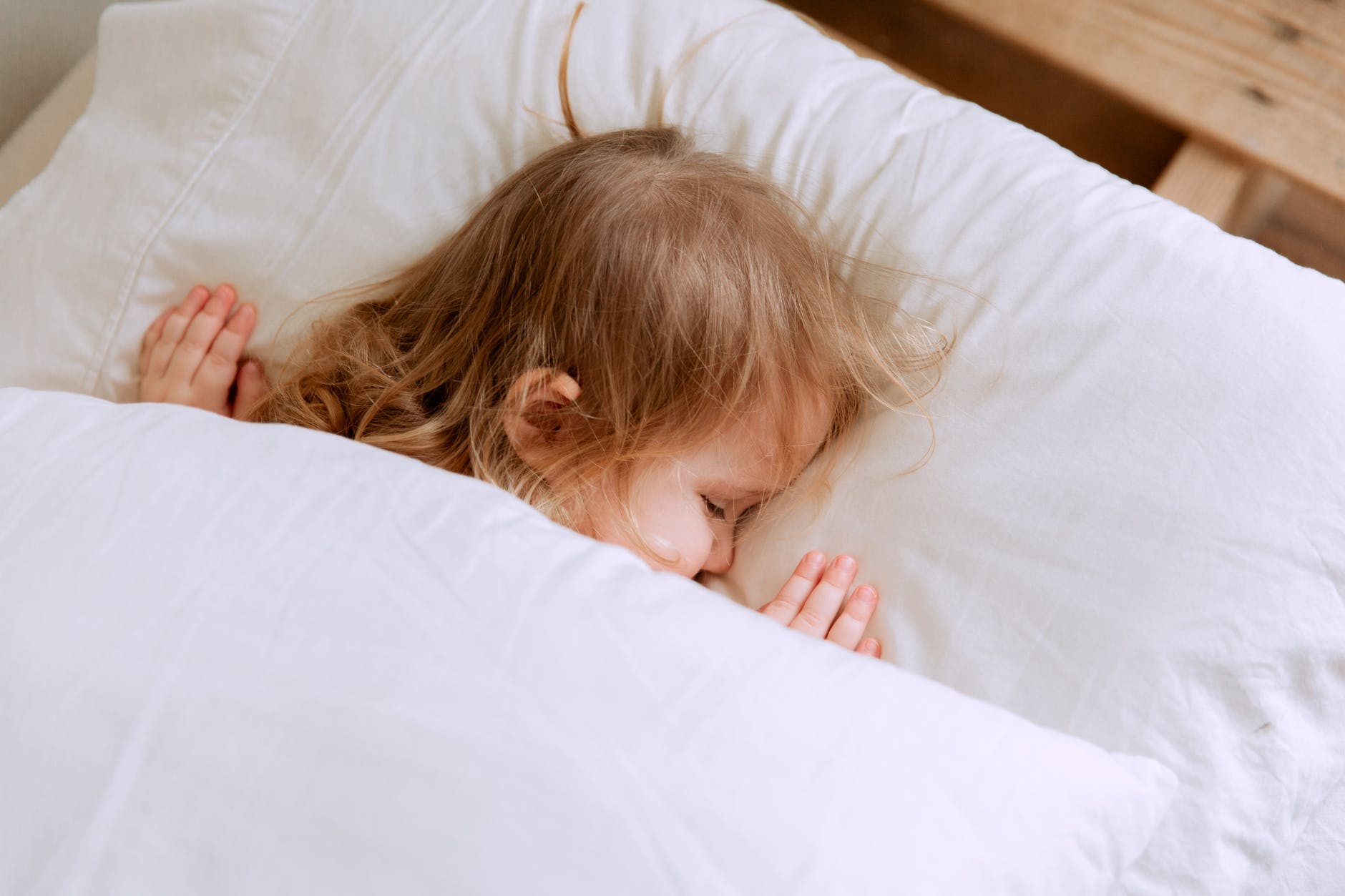 photo of child laying on bed