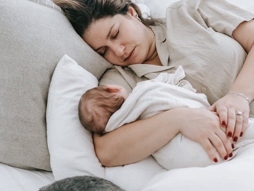 young mom with cute baby and dog sleeping on bed